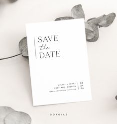 the save the date card is next to some flowers and leaves on a white surface