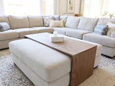 a living room with a large sectional couch and coffee table in the middle, on top of a rug