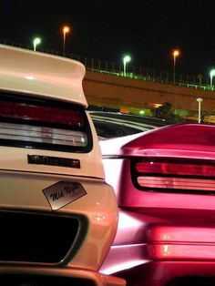 two cars parked next to each other in a parking lot at night with lights on