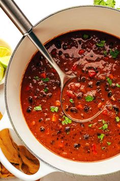 a white bowl filled with chili, beans and tortilla chips on top of a table