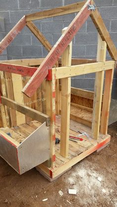 a small wooden house made out of pallet wood and some construction tools on the ground