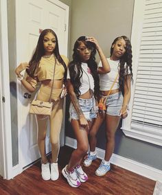 three young women standing in front of a door with their hands on their hipss