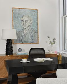 an office with a desk and chair in front of a painting on the wall above it