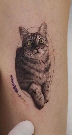 a cat tattoo on the side of a woman's leg, with lavenders around it