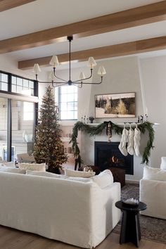 a living room filled with white furniture and a christmas tree in the middle of it