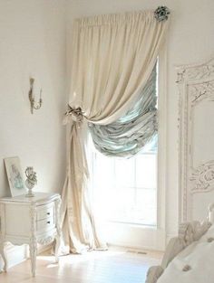 a bedroom with a bed, dresser and window covered in draping on the curtains