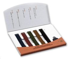 four different colored pens in a box on a white background with an information card behind them