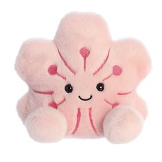 a pink stuffed animal with hearts on it's face and eyes, sitting against a white background