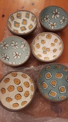 four bowls with flower designs on them sitting on a table