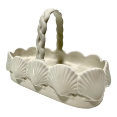 a white shell shaped basket is shown on a white background, with the handle extended to it's left side