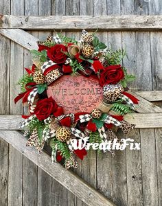 a welcome wreath with red roses and leopard print ribbon hanging on the side of a wooden wall