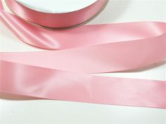 a roll of pink satin ribbon sitting on top of a table