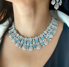 Explore our silver diamond necklace set adorned with light blue stones, perfectly matched with statement long earrings. This high-quality cubic zirconia set is ideal for brides, engagements, or cocktail parties, adding a touch of elegance and sparkle to any special occasion. Earrings are 2.7 inches Long    Earrings are 1.2 Inches Wide  A Earring Weight is 0.5 oz  our products are crafted using traditional skills from our rich heritage. The manual nature of these crafts means that irregularities Silver Diamond Necklace, Cocktail Jewelry, Diamond Necklace Set, Indian Wedding Jewelry, Bridal Jewelry Sets, Bridal Sets, Silver Diamonds, Blue Stone, Long Earrings