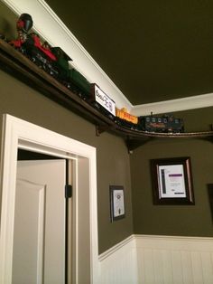 a toy train is coming down the track on top of a wall above a doorway