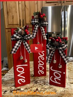 three red christmas gift bags with the word love hanging from them on a kitchen counter