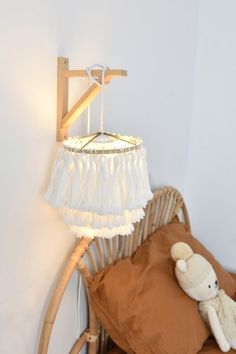 a teddy bear sitting on top of a bed next to a wooden frame and lamp