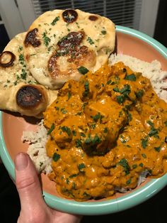 a person holding a plate with some food on it and rice in front of them