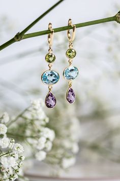 Add a touch of radiance and sophistication with these striking triple drop gemstone earrings comprising of a circular peridot, oval blue topaz and a teardrop amethyst gemstones set in 18ct gold vermeil. These earrings are so elegant you will want to wear them time and time again. They are fitted  with a secure english lock fastening. Total Drop 49mm, Amethyst 12 x 8mm, Blue Topaz 9 x 11mm and Peridot 6mm. All the raw gemstones we use have been selected for their uniqueness and originality as well their quality and colour 925 Silver is the base metal  and all our silver is nickel free. Luxury gift wrapping available. Luxury Gemstone Teardrop Dangle Earrings, Luxury Gemstone Teardrop Earrings As Gift, Luxury Teardrop Earrings With Gemstone, Luxury Teardrop Amethyst Gemstones, Luxury Blue Topaz Teardrop Earrings, Luxury Blue Topaz Teardrop Jewelry, Luxury Gold Teardrop Earrings With Gemstones, Luxury Teardrop Blue Topaz Earrings, Luxury Gemstone Teardrop Earrings