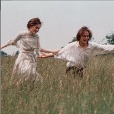 two people are running through the tall grass