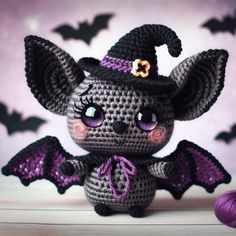 a small crocheted bat with purple eyes and a hat on it's head