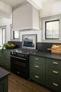 a stove top oven sitting inside of a kitchen next to green cabinets and counter tops