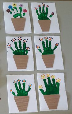 four cards with handprinted cactus in a pot on top of a table next to flowers