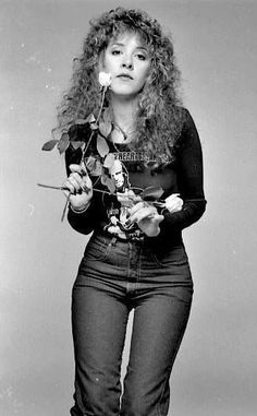 a black and white photo of a woman holding a rose in her right hand,