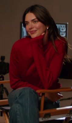 a woman sitting in a chair with her hand on her face and smiling at the camera