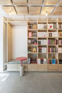 an empty room with bookshelves and a red table in front of the bookcase