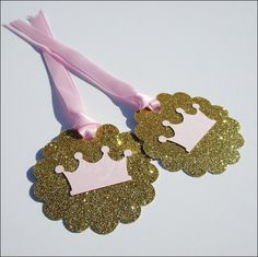 two pink and gold princess crowns on top of each other with a pink ribbon in the middle