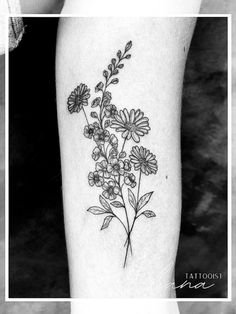 a black and white photo of flowers on the leg, with an inscription that reads tattoo