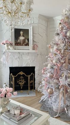 a white christmas tree with pink and gold ornaments in front of a fireplace mantel