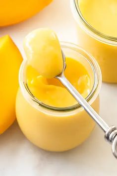 two jars filled with yellow jello sitting on top of a white counter next to bananas