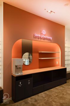 the inside of a pharmacy with an orange wall and black cabinets, mirrors and drawers