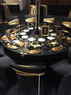 a round table with black and gold plates, silverware and place settings on it