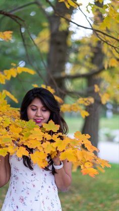 a woman in a white dress holding onto yellow leaves