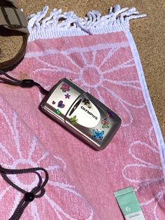 a cell phone sitting on top of a pink towel next to sunglasses and an eyeglass case