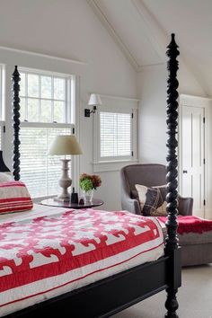 a bedroom with four poster bed, chair and lamp on the side table in front of it