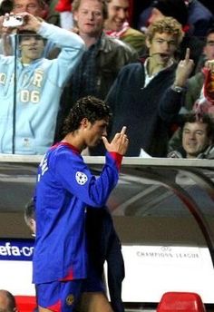 a soccer player walking on the sidelines with his hand up in front of him