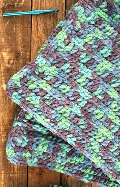 a crocheted dishcloth on top of a wooden table next to a pair of scissors