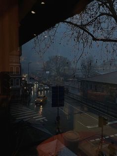 a rainy street with cars parked on the side of it