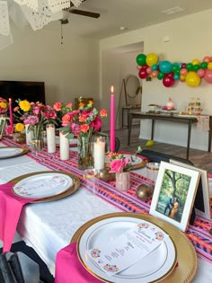 a long table with plates, candles and flowers in vases on top of it