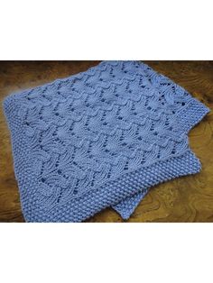 a blue knitted blanket sitting on top of a wooden floor