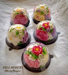 four cakes decorated with flowers and leaves on top of a white cloth covered tablecloth