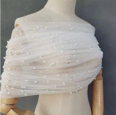 a mannequin wearing a white dress with pearls on it