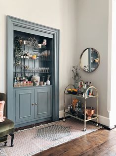 a living room filled with furniture next to a wall mounted shelf full of bottles and glasses