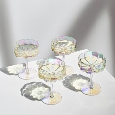 four wine glasses sitting on top of a white table next to each other and one is empty