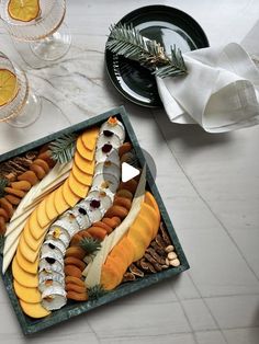 a platter filled with fruit and nuts on top of a white tiled floor next to wine glasses