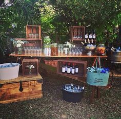 an outdoor bar is set up with bottles and buckets on the table for drinks