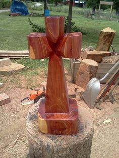 a wooden cross sitting on top of a tree stump in a yard with other woodworking tools